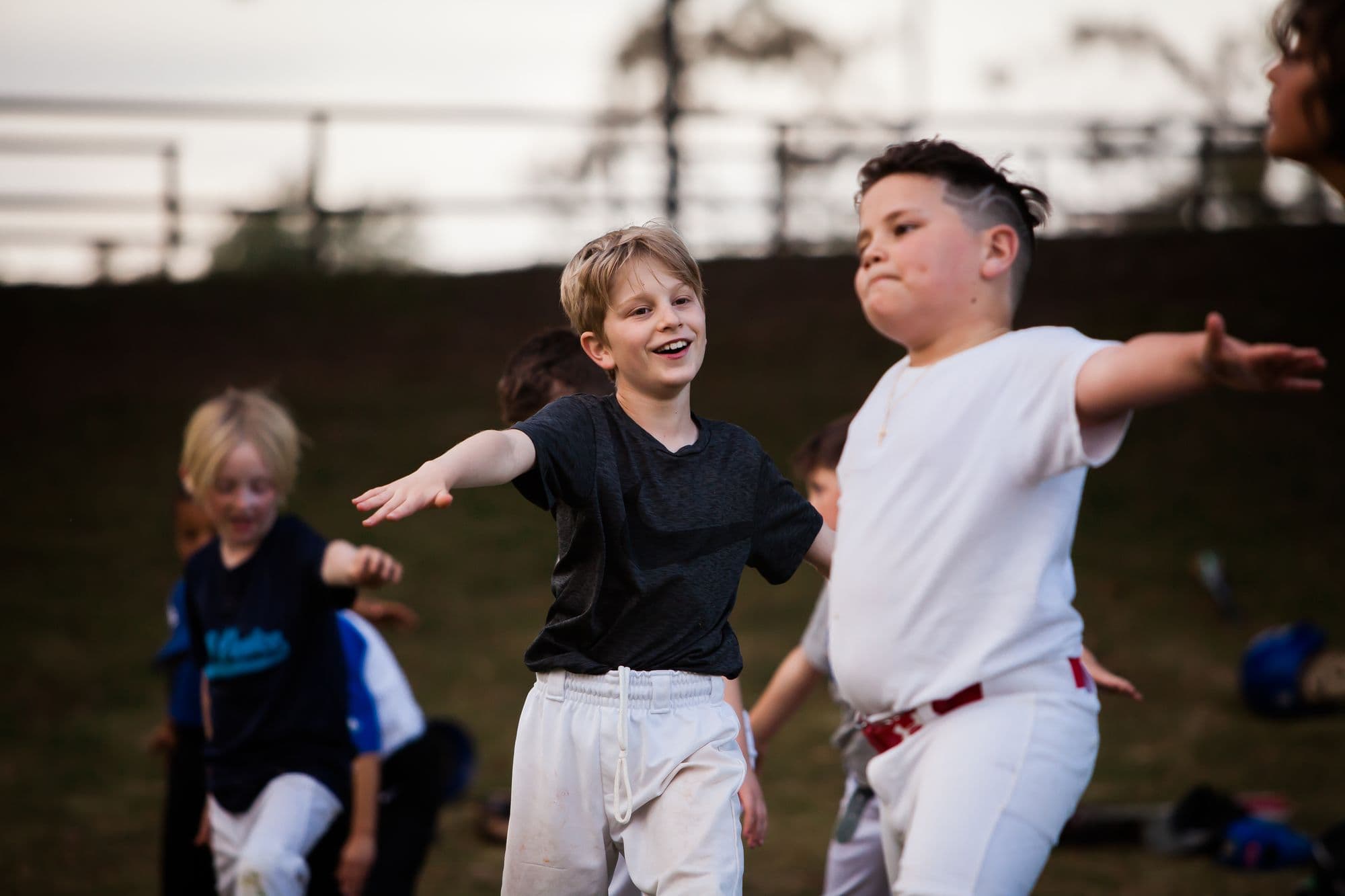 Two young players laughing with their arms out during a camp warm-up