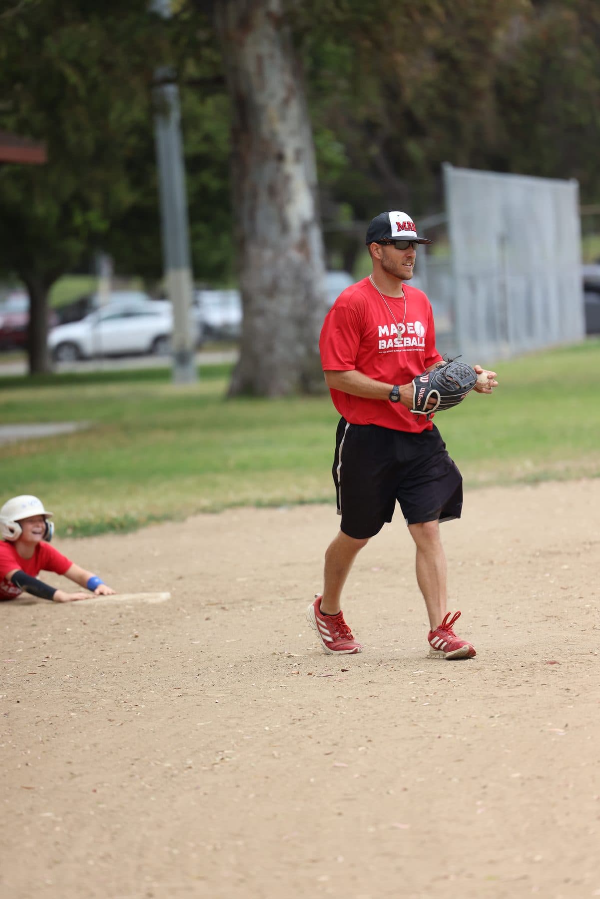 Coach Isaac Hess standing between reps with his glove low on the infield