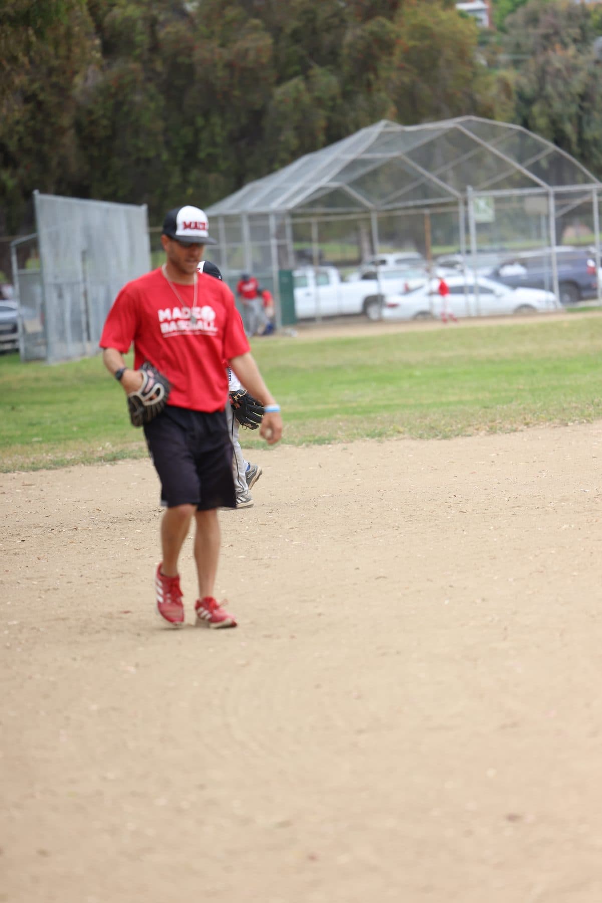 Coach Isaac Hess standing ready with his glove low during a fielding drill