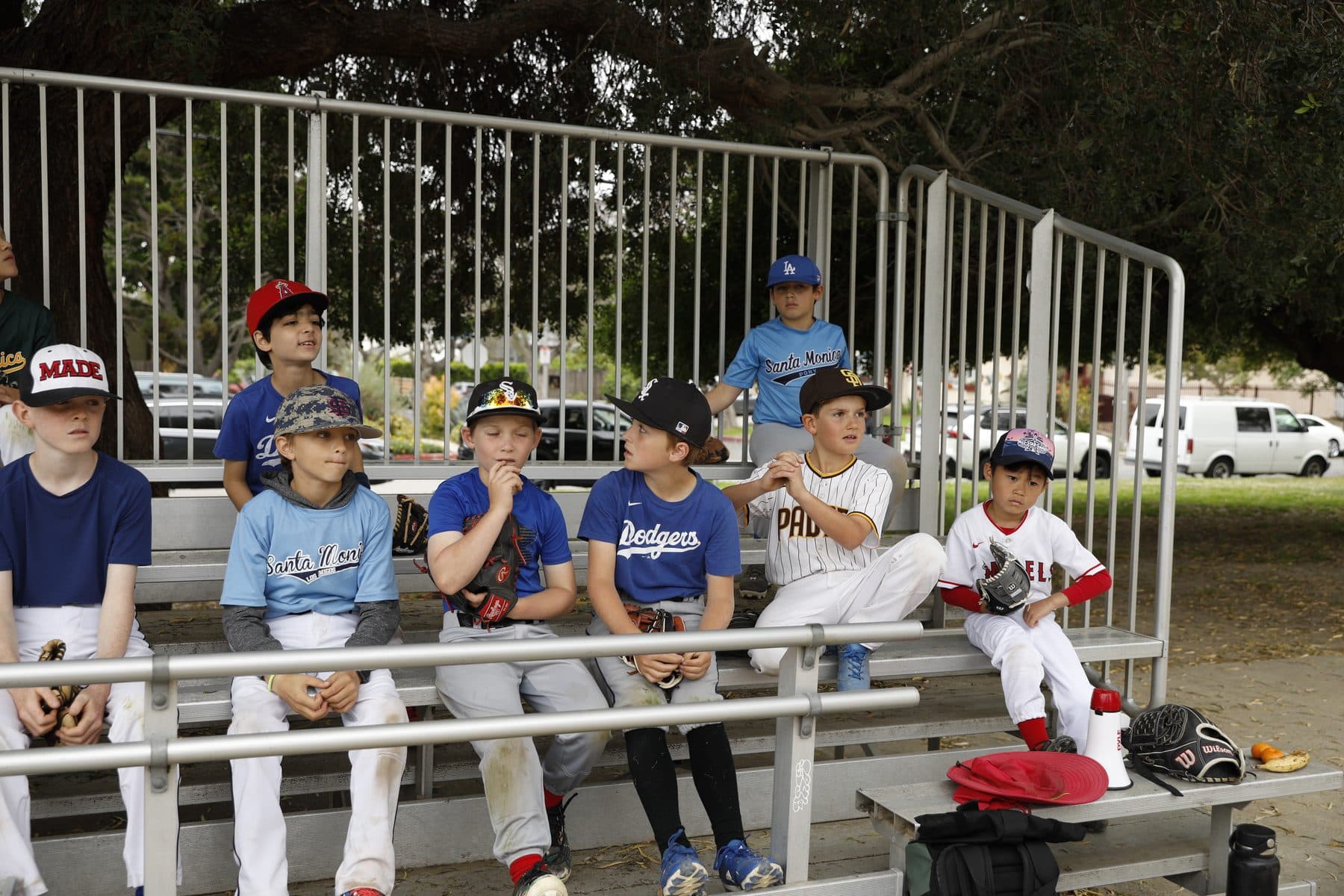A row of young players in team uniforms seated on a bench between drills