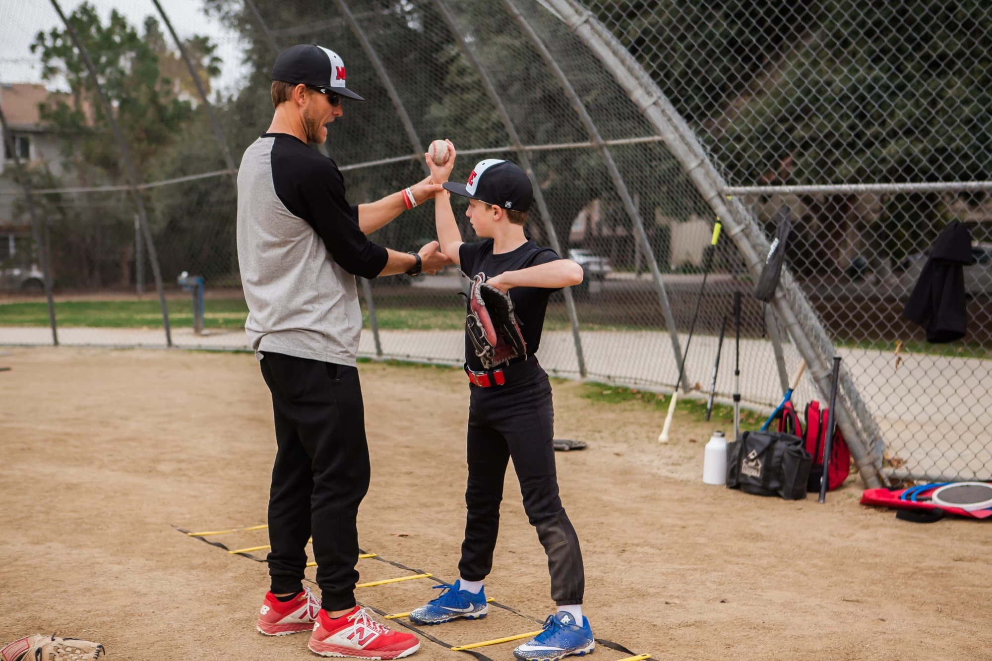 Coach Isaac Hess guiding a young player's throwing grip during a private baseball lesson