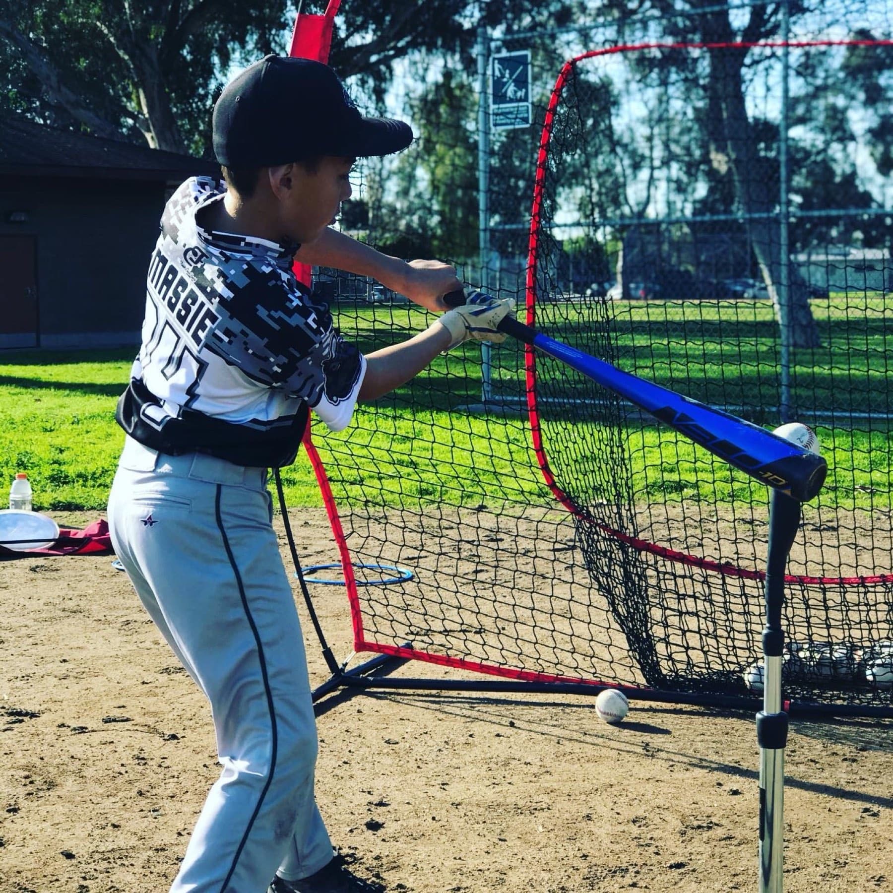 A young hitter making contact off a tee during a hitting lesson