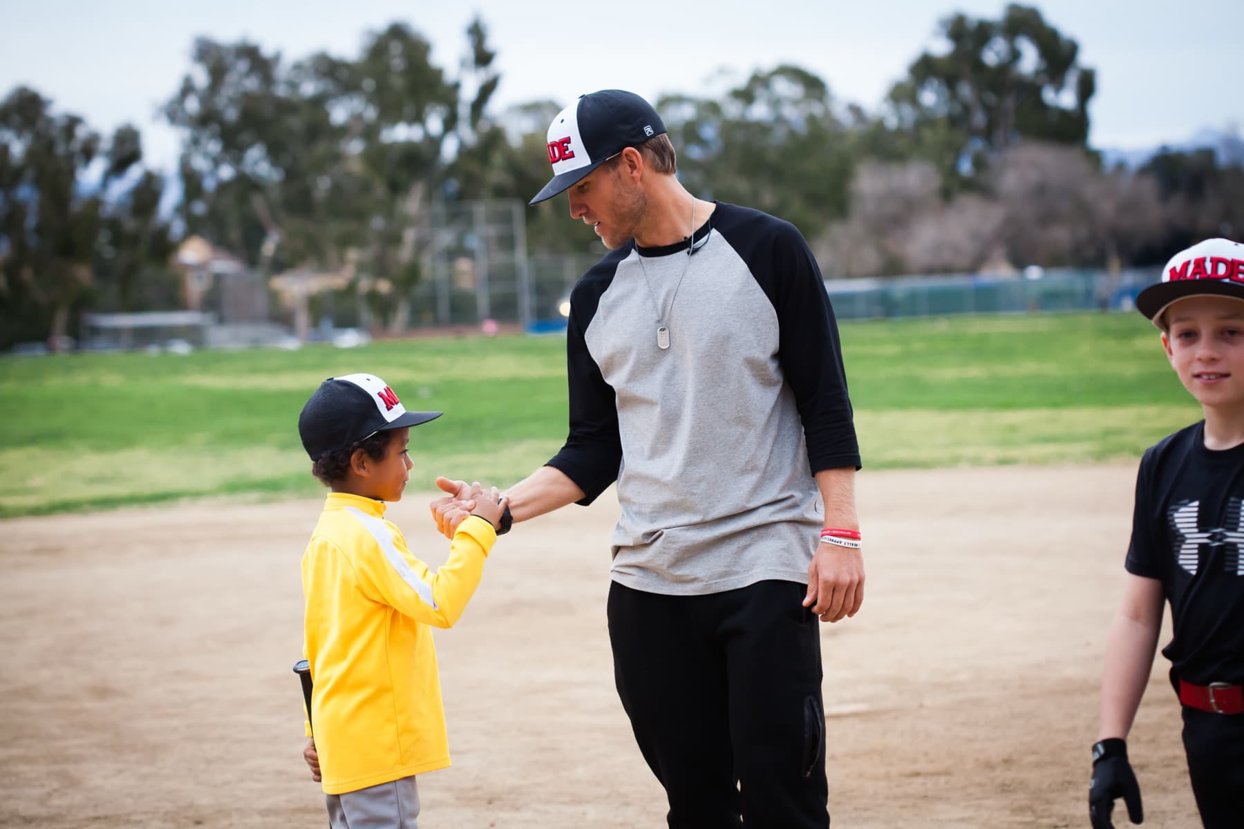 Coach Isaac Hess giving a young player in a yellow jacket a fist bump
