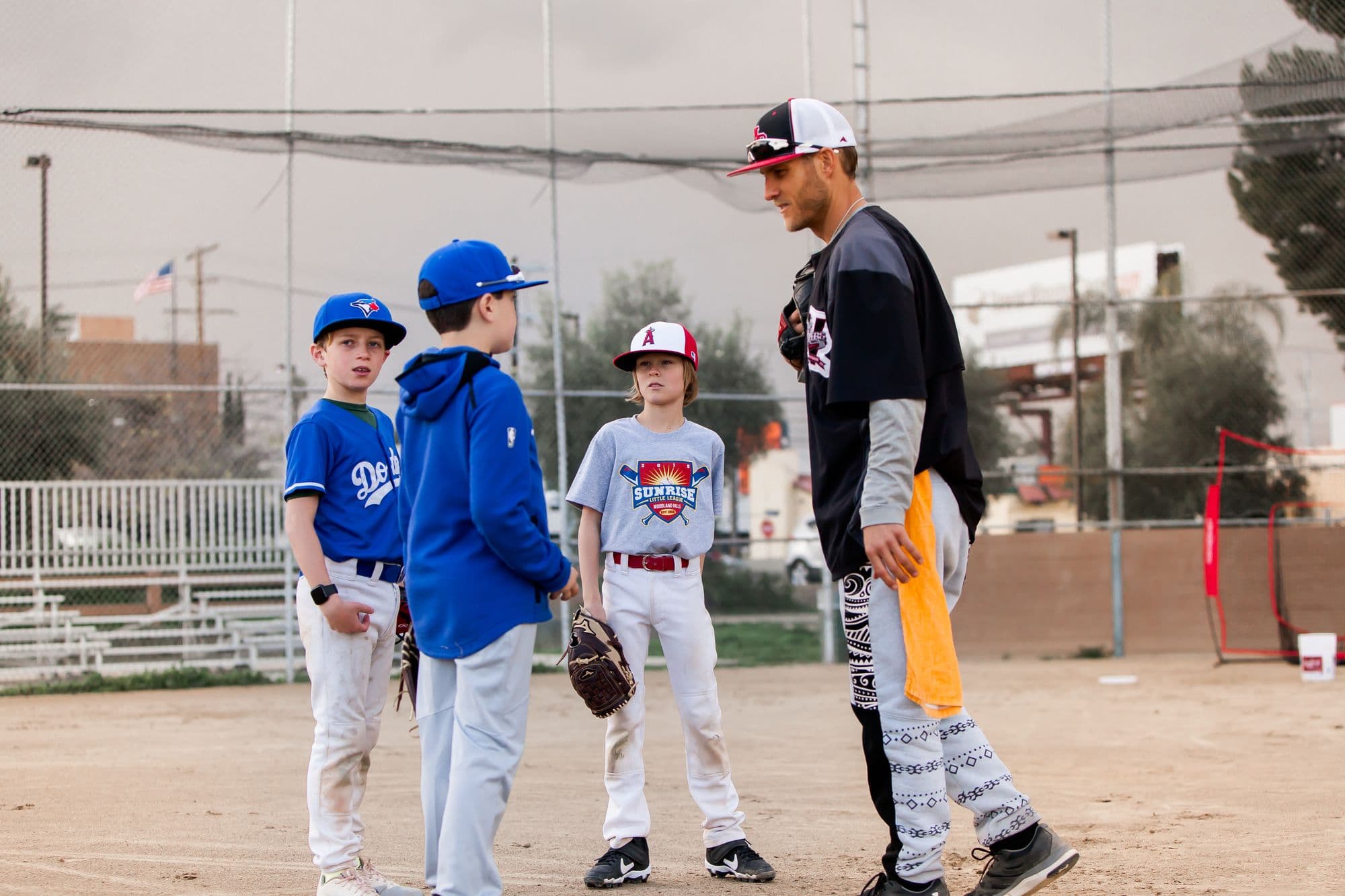 Coach Isaac Hess talking with a group of young pitchers between reps on the mound